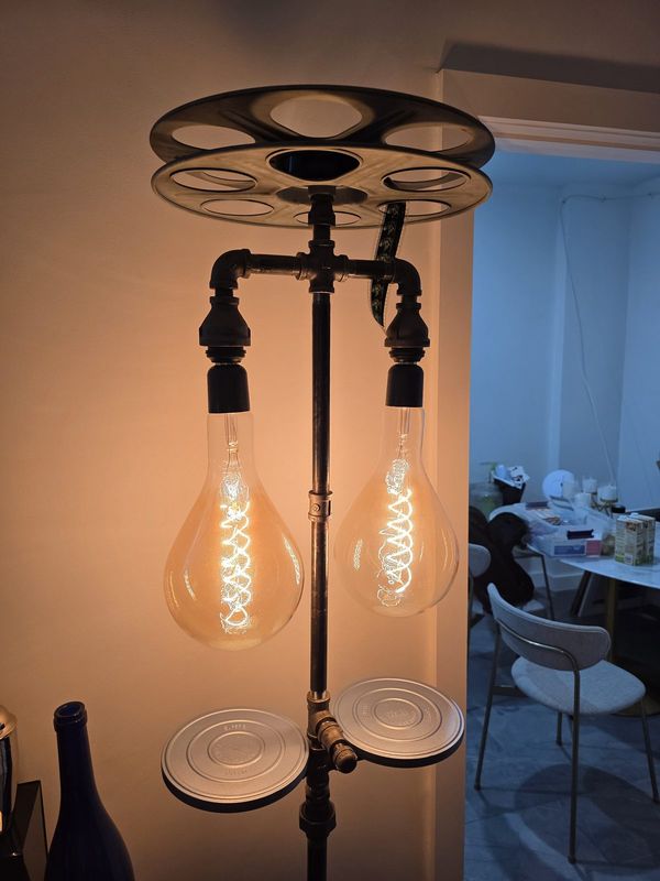 Film reel pipe floor lamp with two big spiral-filament bulbs