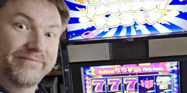 Brett smiling next to the Super Jackpot Party slot machine showing 777